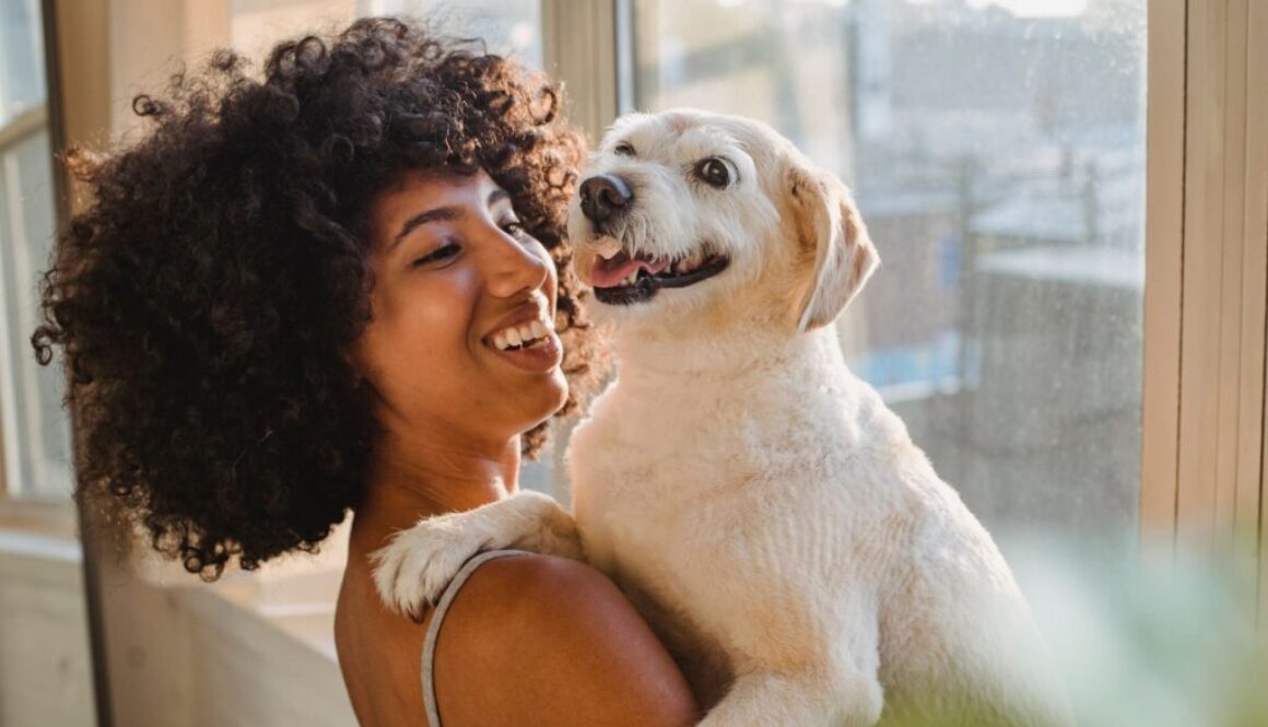 woman with curly hair holding a white dog