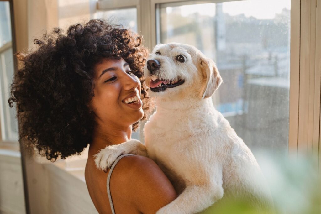 woman with curly hair holding a white dog